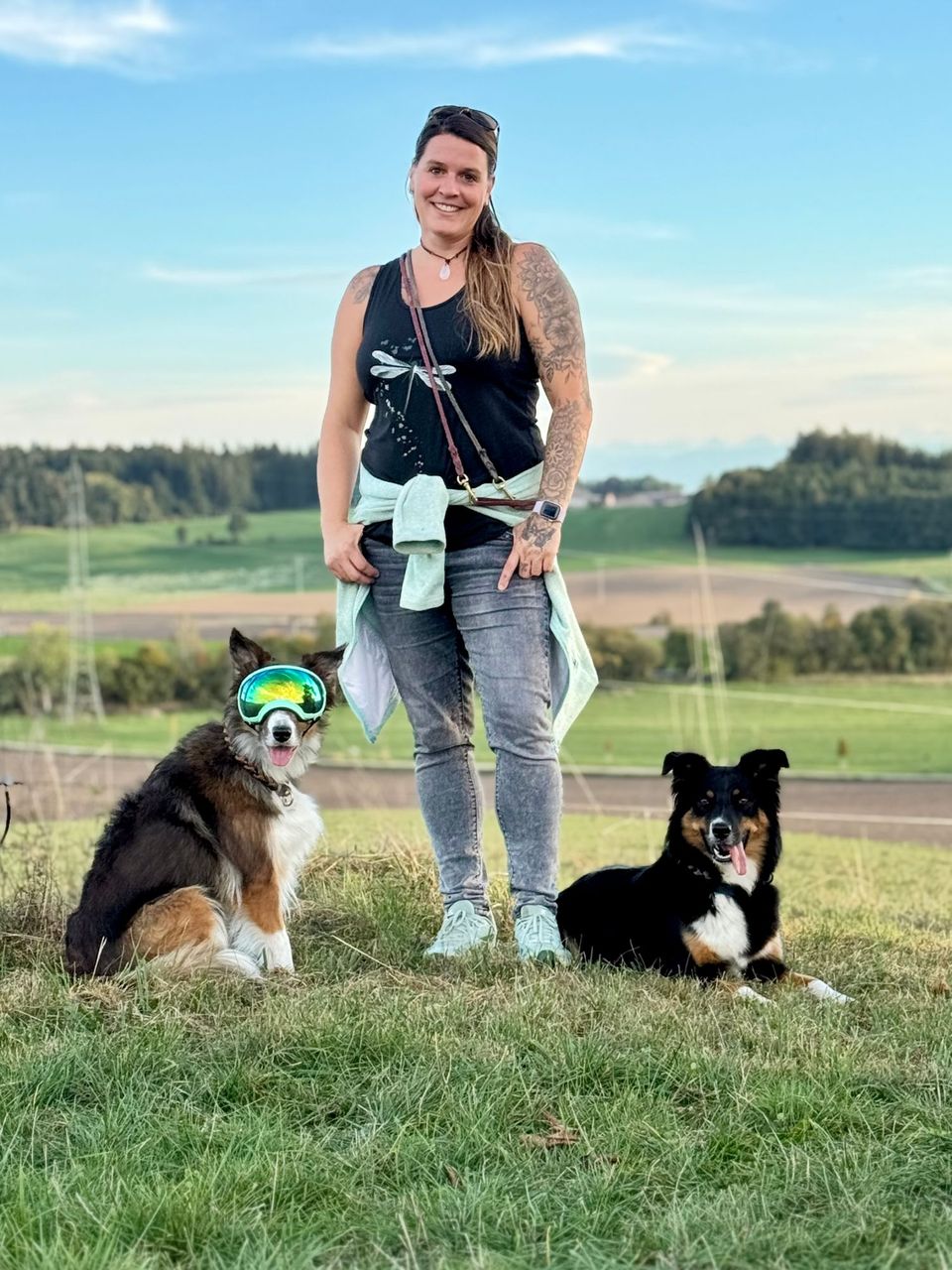 Evi von Pfotensprache mit ihren beiden Hunden auf einer Wiese in Oberbayern
