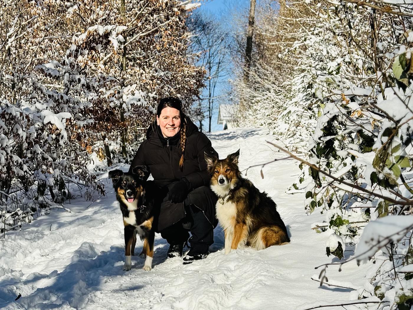 Evi mit ihren beiden Hunden auf einem verschneiten Waldweg in Oberbayern
