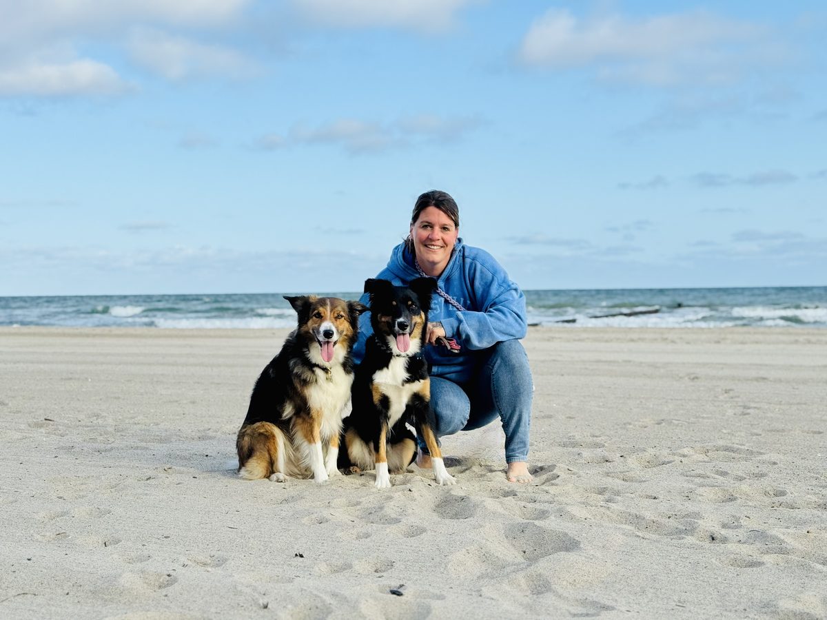 Evi von Pfotensprache mit ihren beiden Hunden am Strand